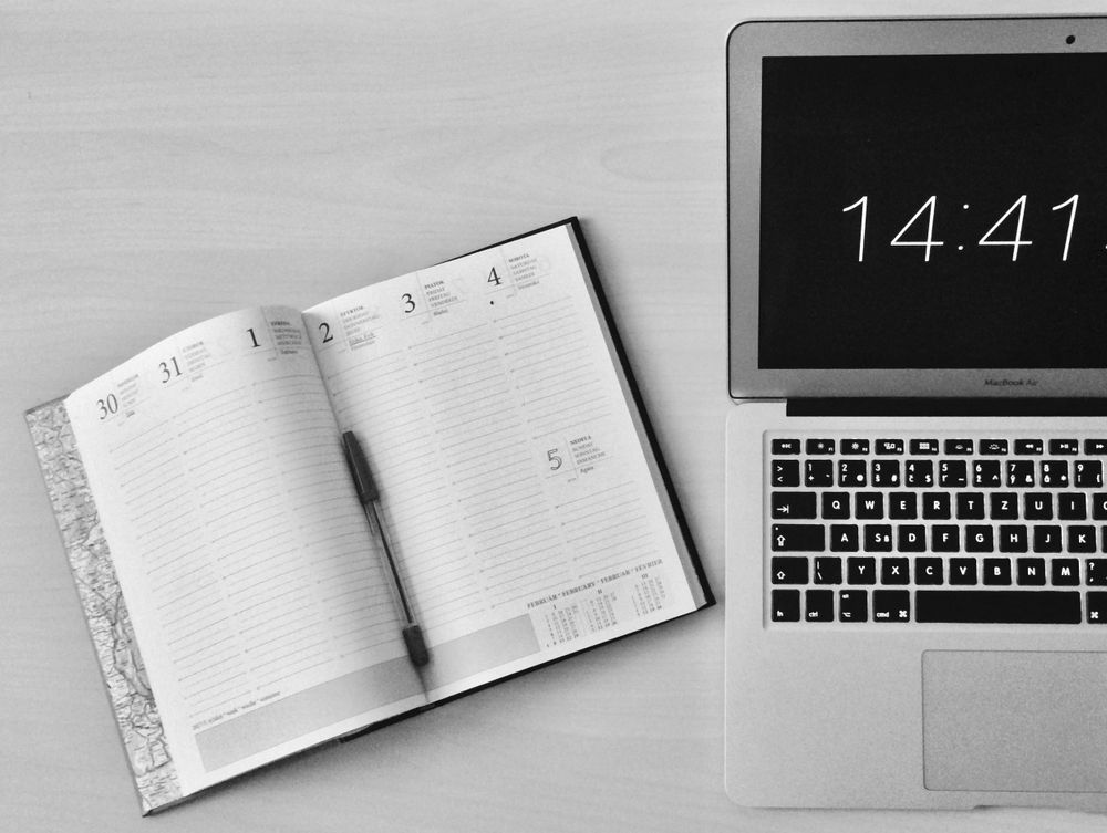Open notebook beside a MacBook on a desk
