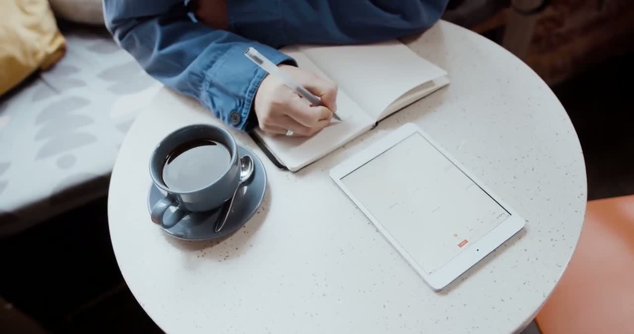 Person using a tablet beside a cup of coffee